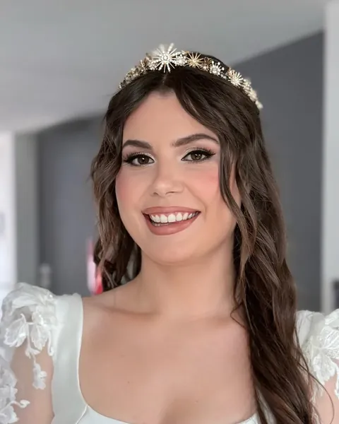 Mujer sonriendo con una diadema de estrellas, el pelo largo ondulado y un vestido blanco con mangas de encaje
