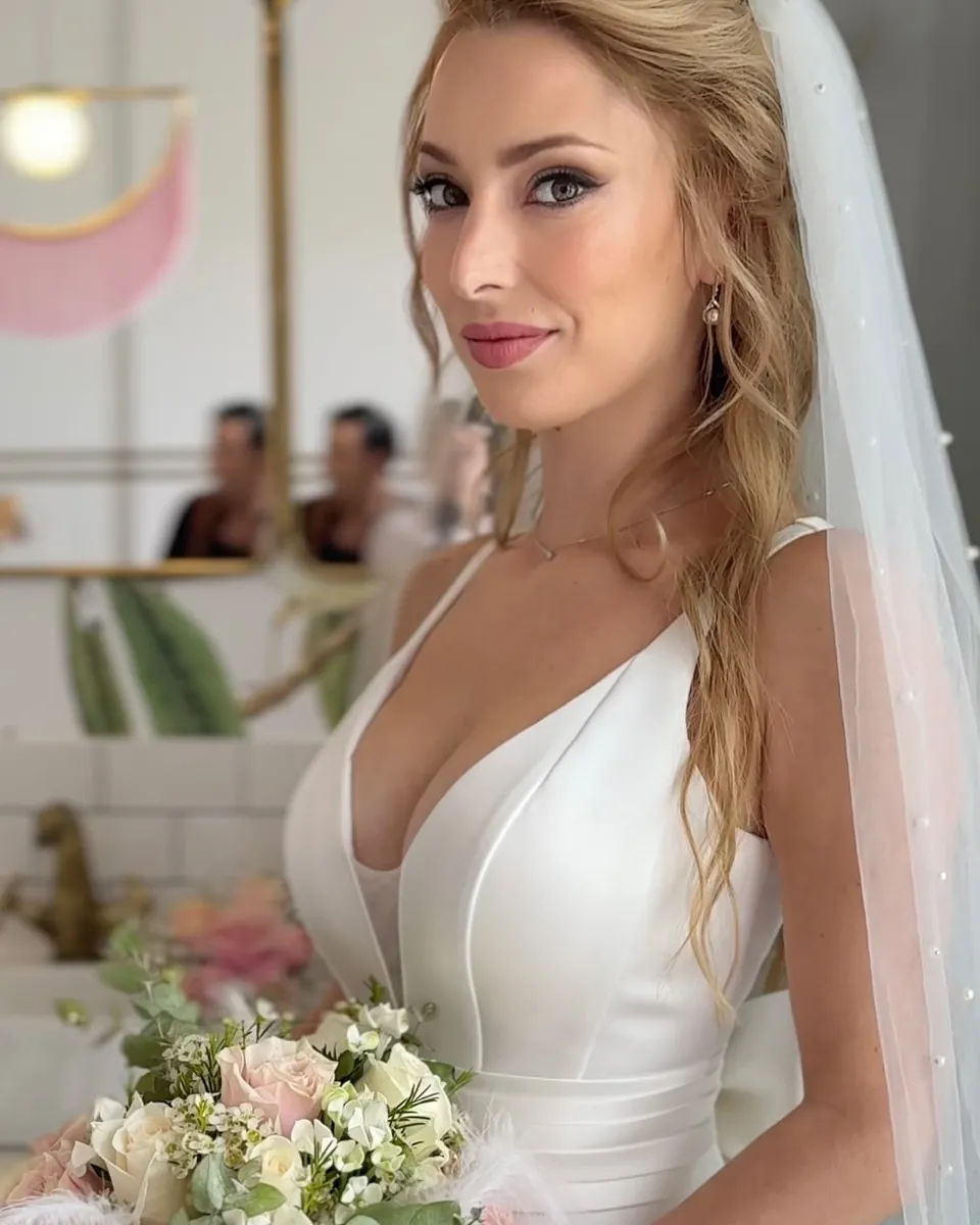 Novia con velo y un ramo de rosas, mirando a cámara