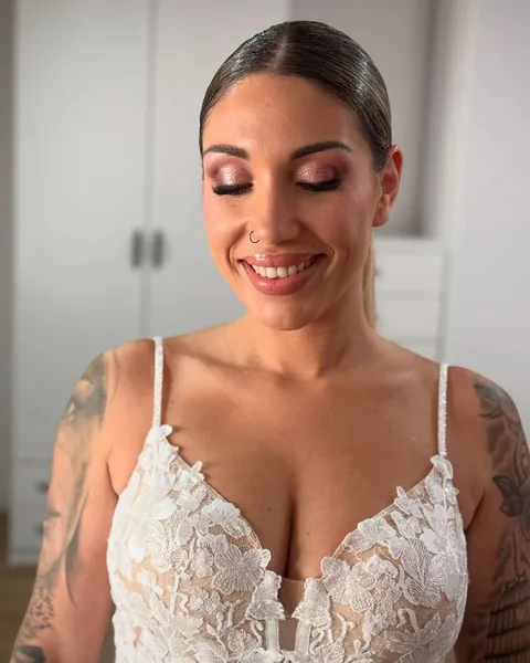Novia con el pelo recogido, los ojos cerrados y la sombra en tonos tierra, con vestido de encaje