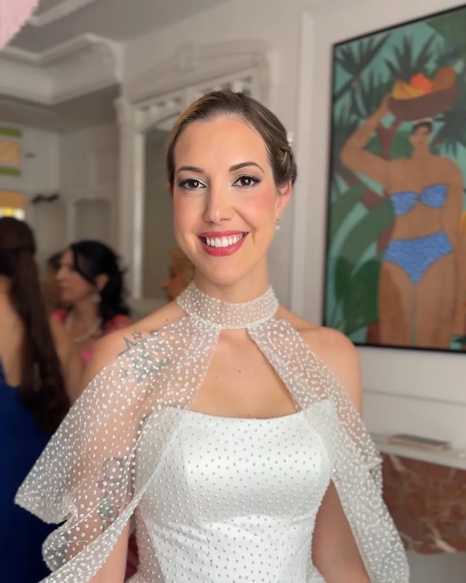 Novia con el pelo recogido y una capa de tul con lunares sobre el vestido, sonriendo en un salón